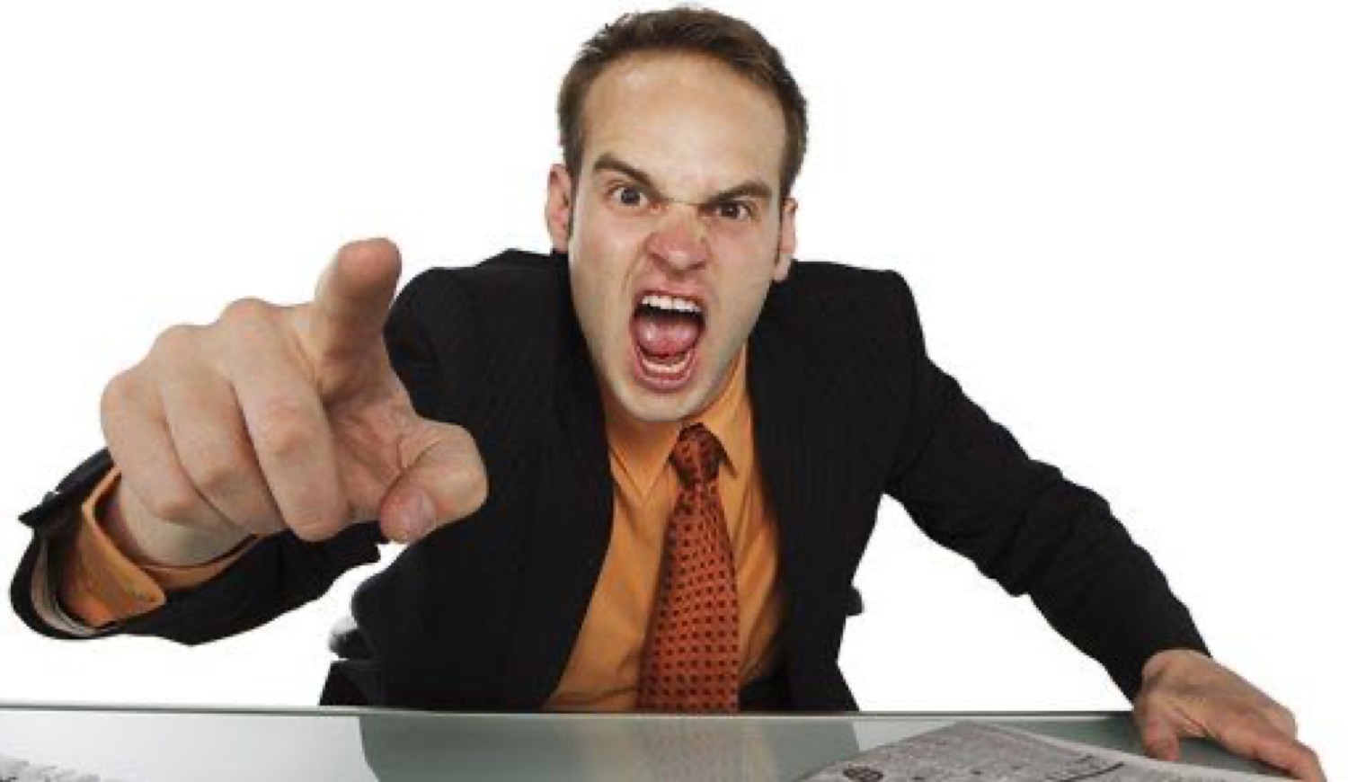 Man in business suit leaning over a desk, furiously pointing and screaming at the camera