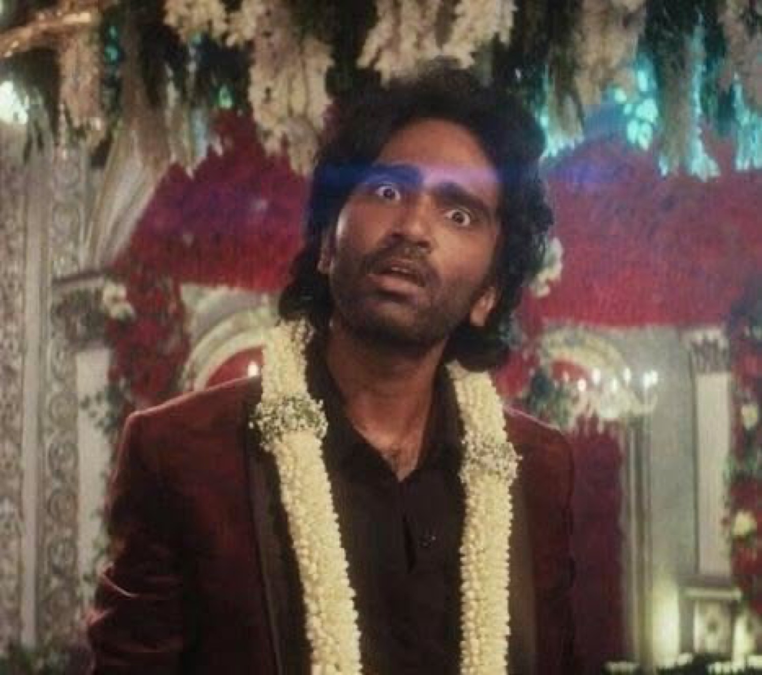 Man in a flower garland staring in shock