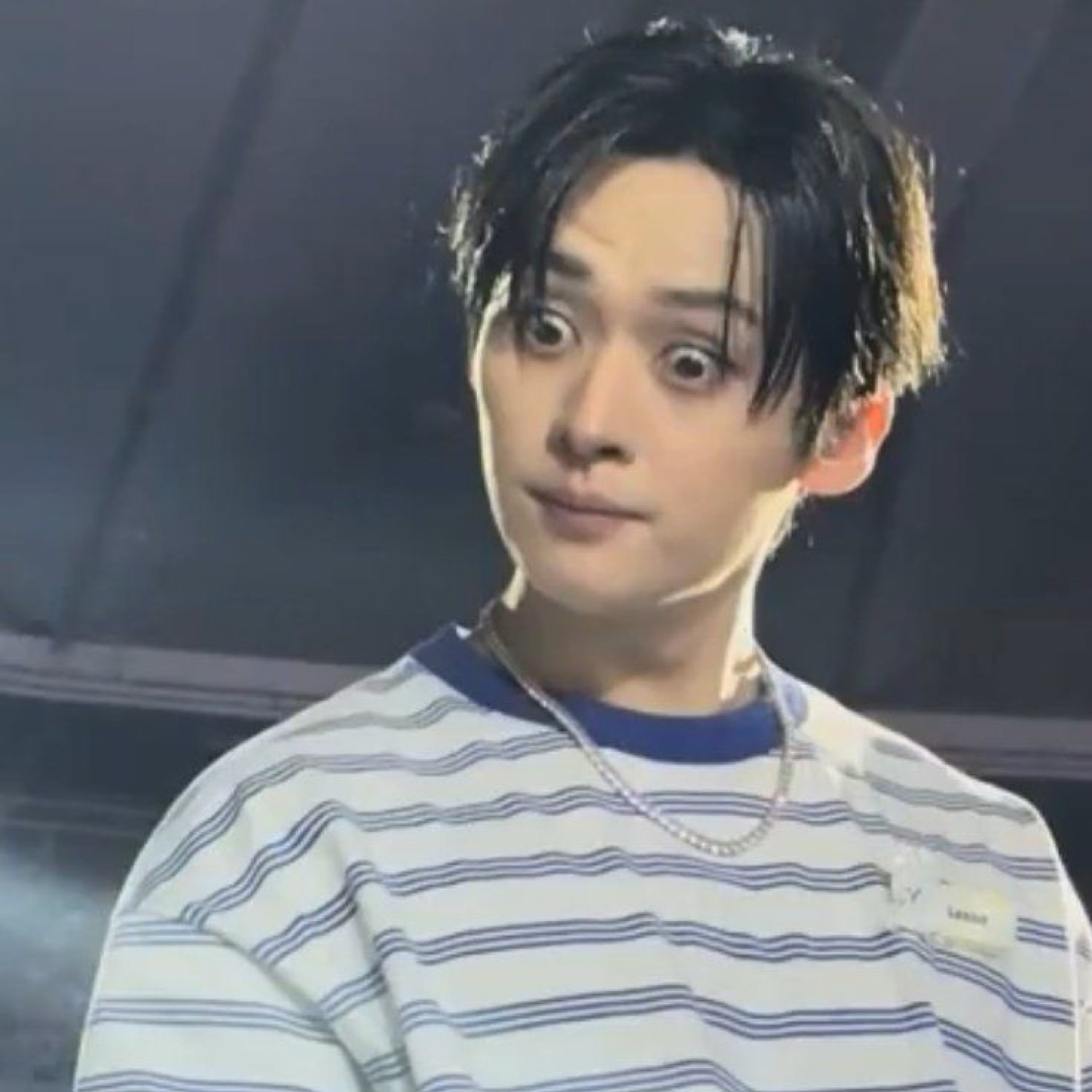 K-pop performer on stage with wide bulging eyes in a startled, frozen stare