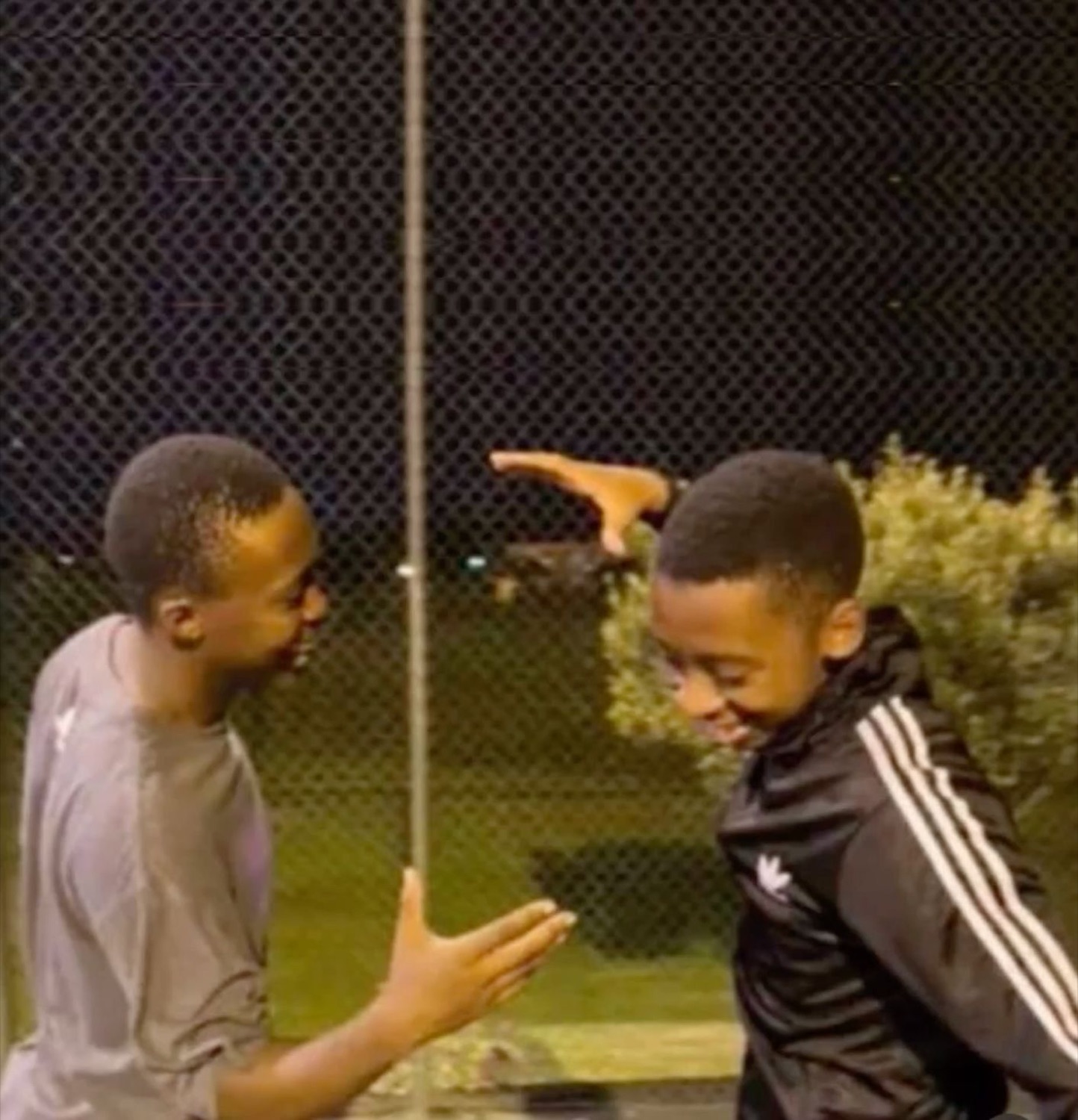 Two teens going in for an excited handshake at a basketball court