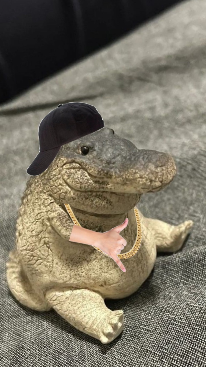 Chubby alligator figurine in a backwards cap holding something