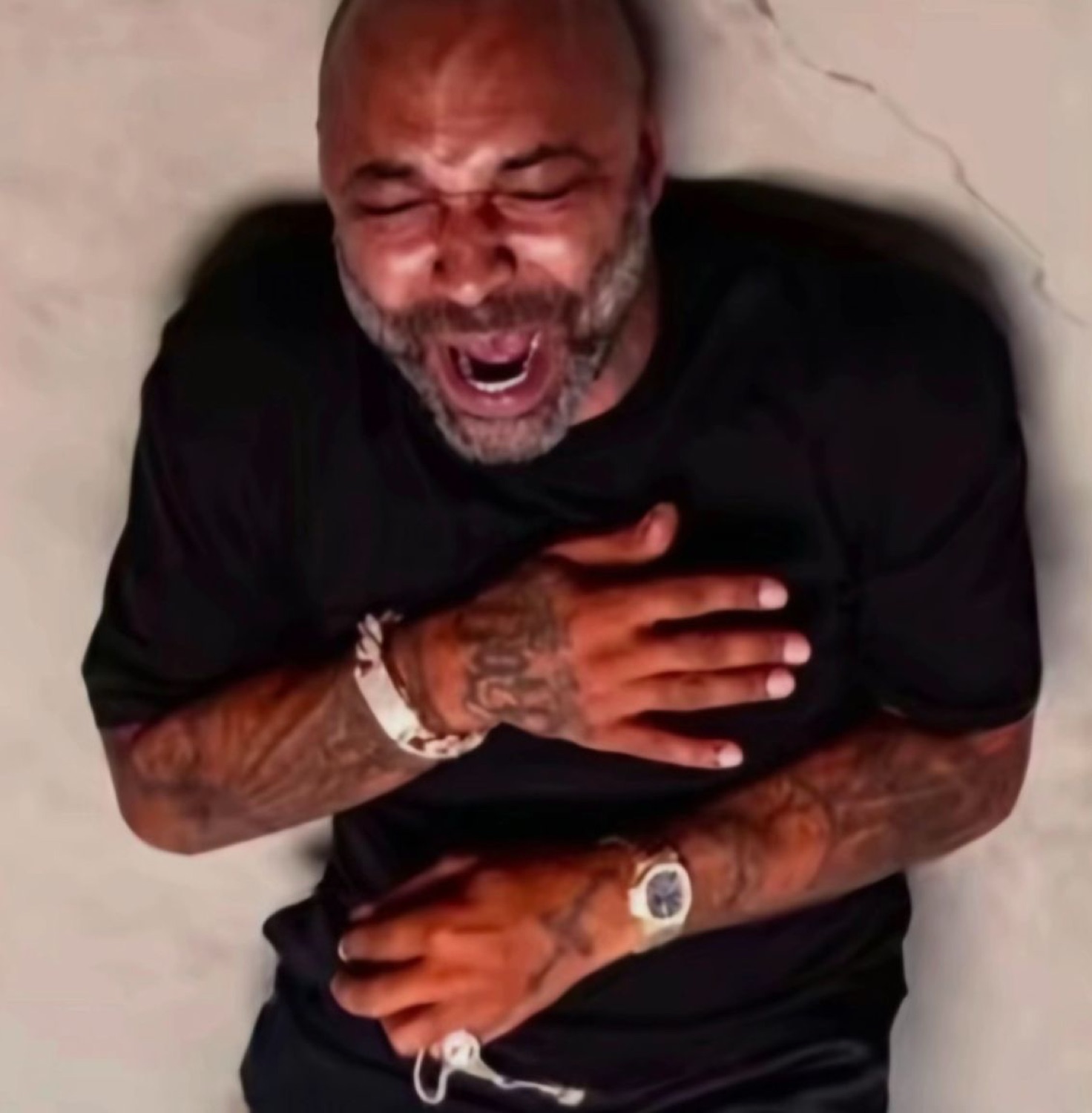 Bald bearded man clutching his chest and wailing with his mouth wide open
