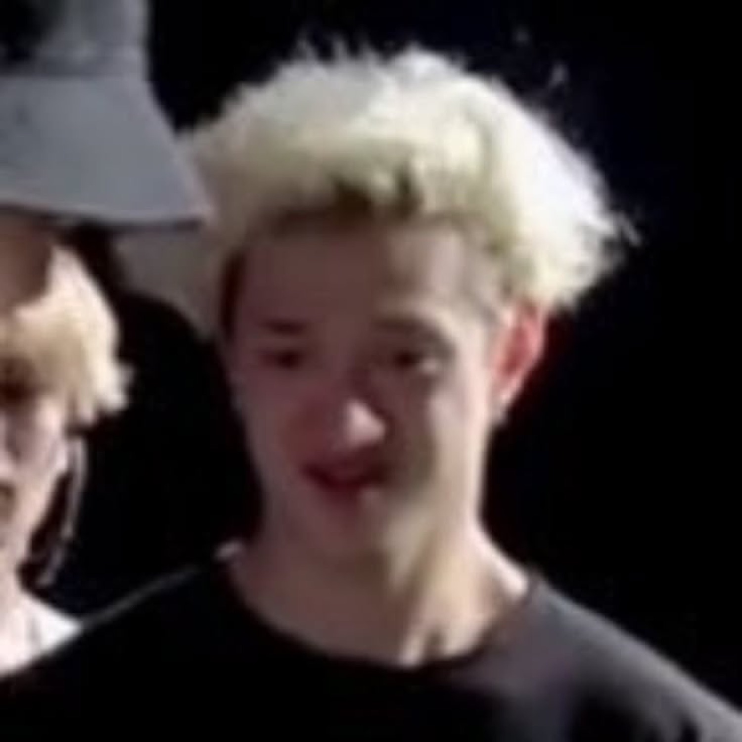 Blond teen on a dark stage making a pained, cringing face