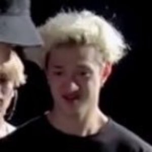 Blond teen on a dark stage making a pained, cringing face