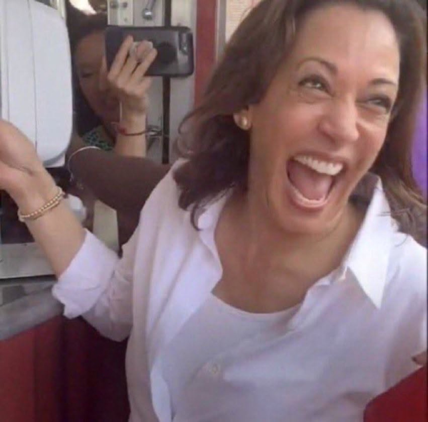 Kamala Harris laughing with full energy, arms wide, completely delighted