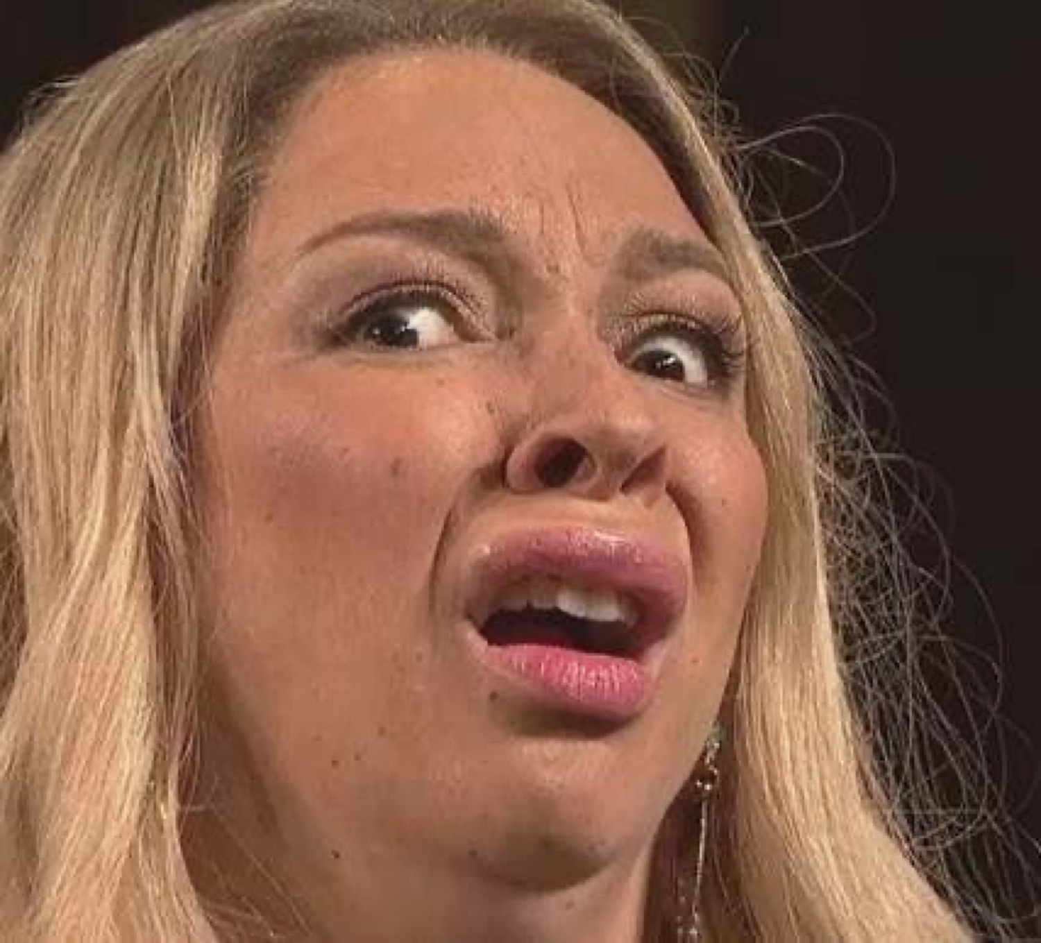 Blonde woman pulling a full repulsed grimace with her lip curled