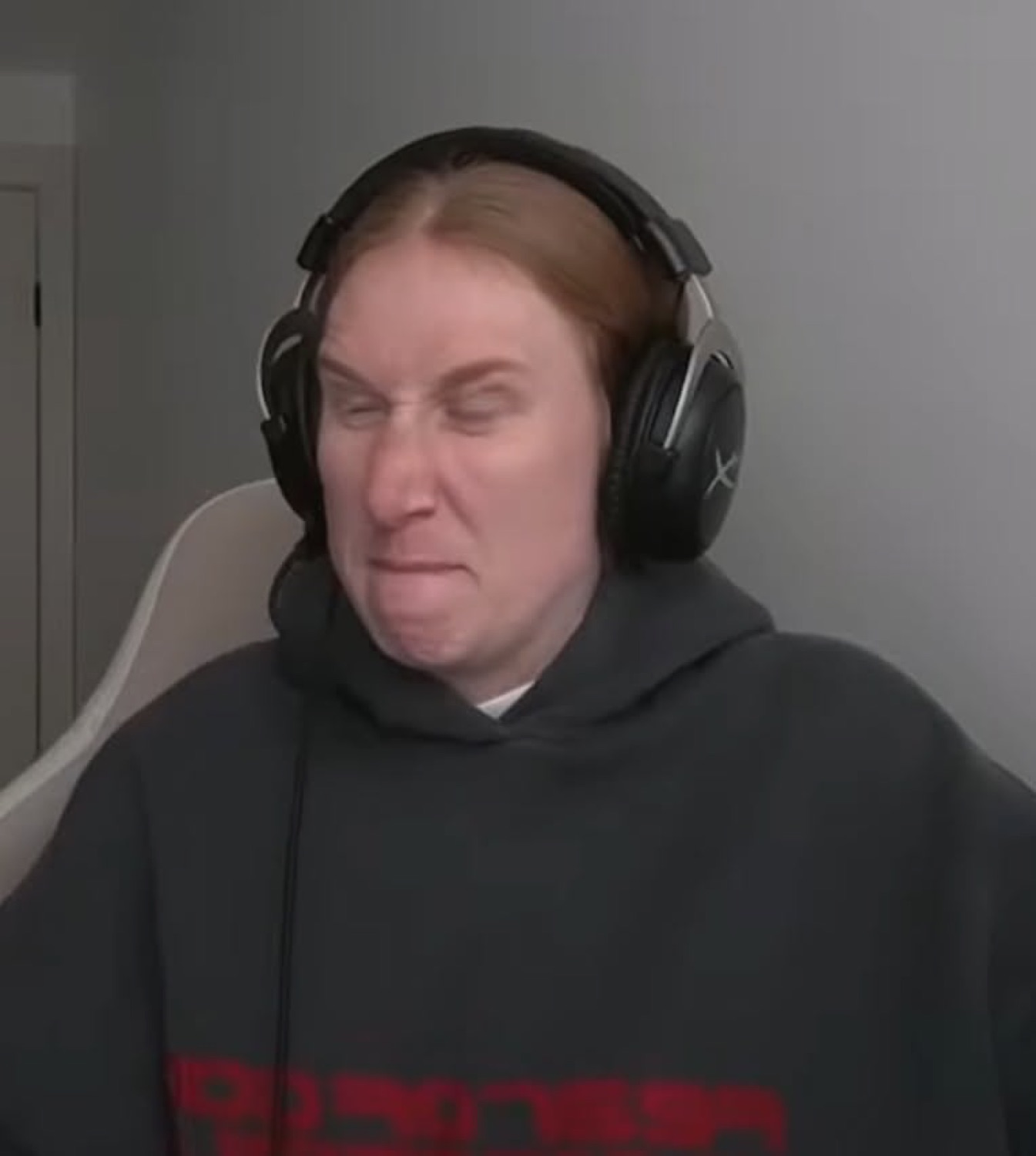 Man in headphones scrunching his face into a cringing disgusted grimace at his desk