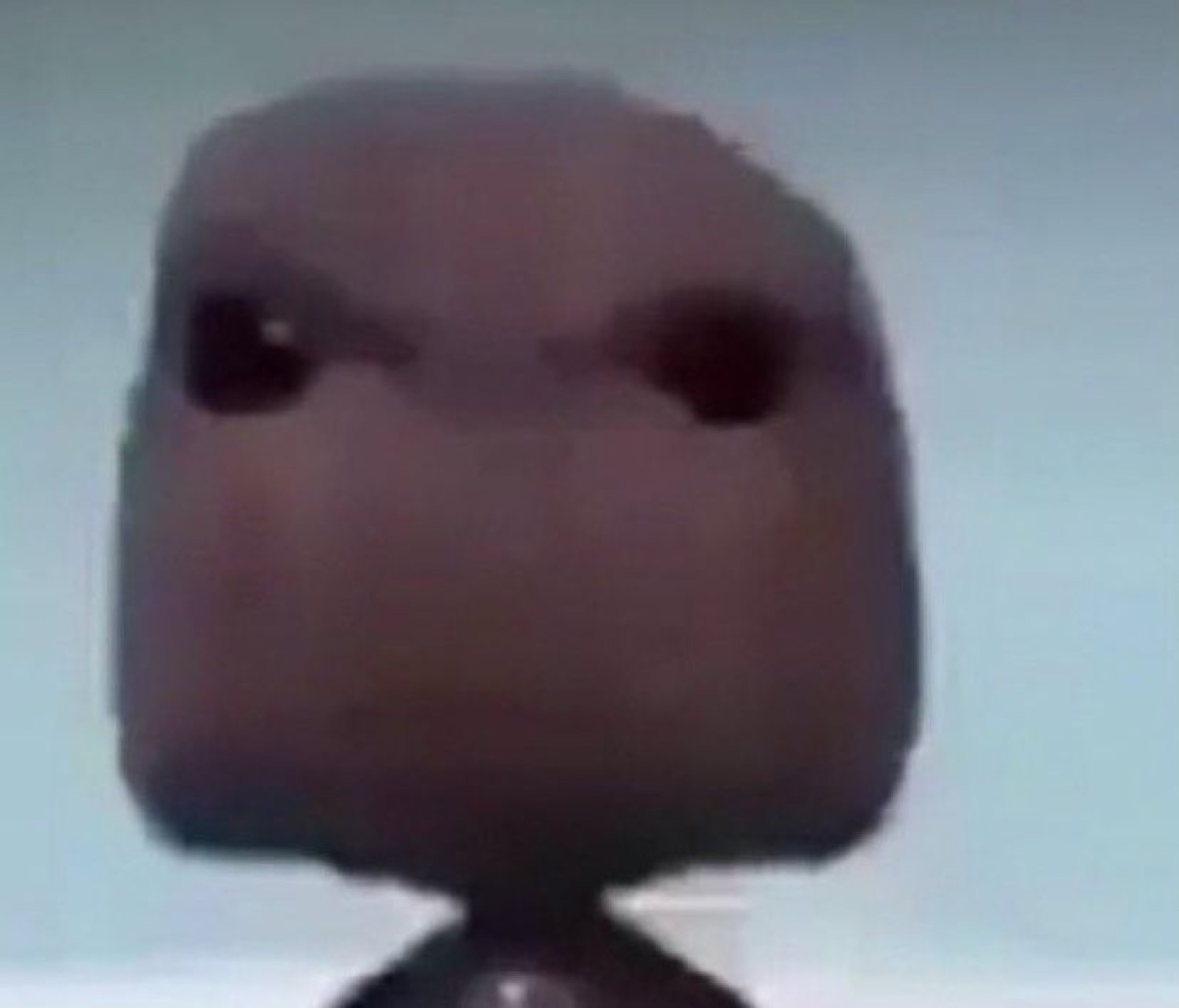 Sackboy staring dead ahead with tiny dark eyes on a flat beige face