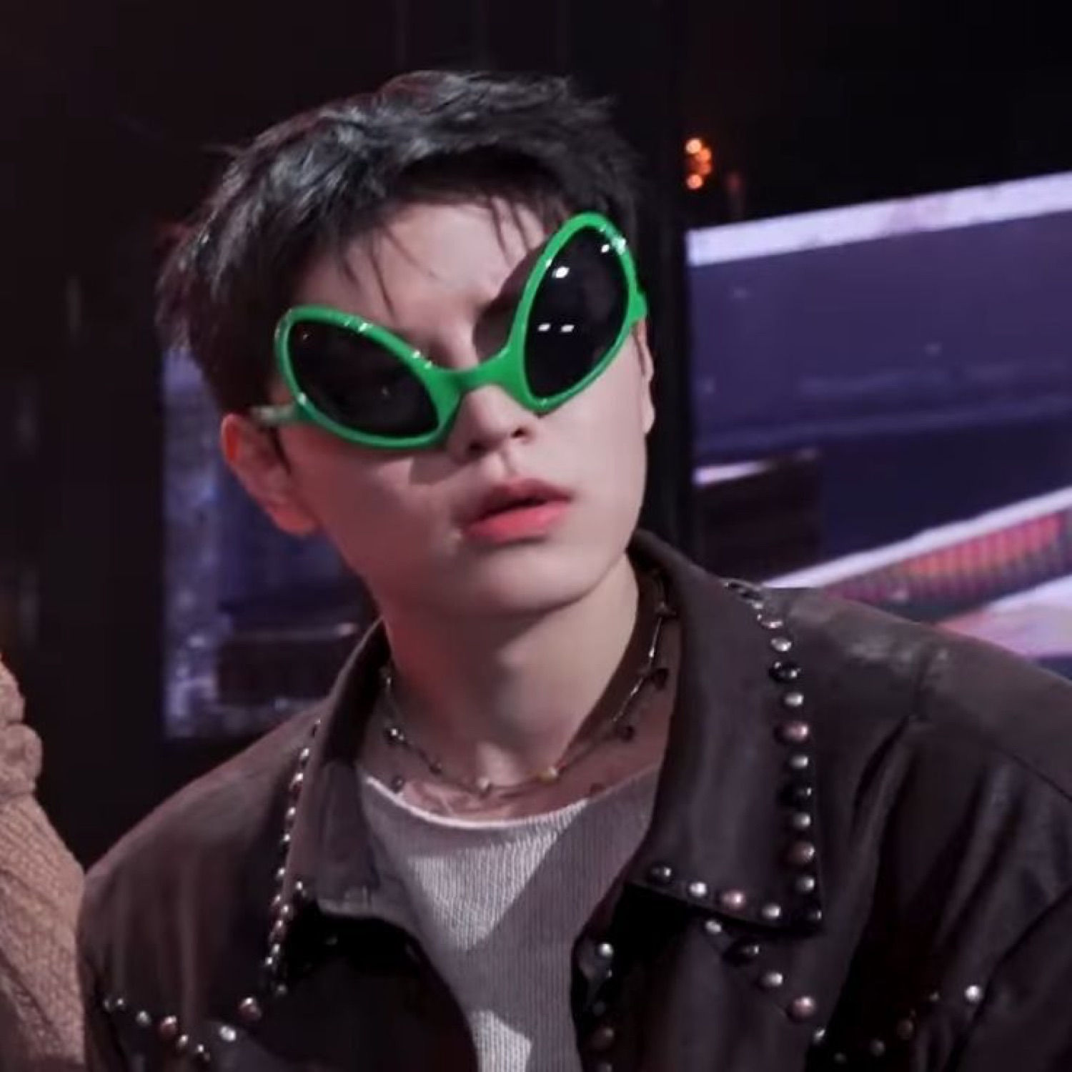 Young man in goofy green alien sunglasses with a cool, deadpan expression