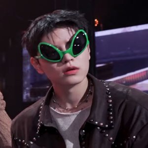 Young man in goofy green alien sunglasses with a cool, deadpan expression