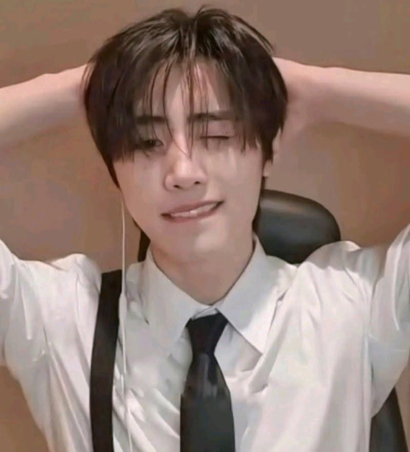 K-pop style guy in a white shirt and tie leaning back with a relaxed satisfied smile