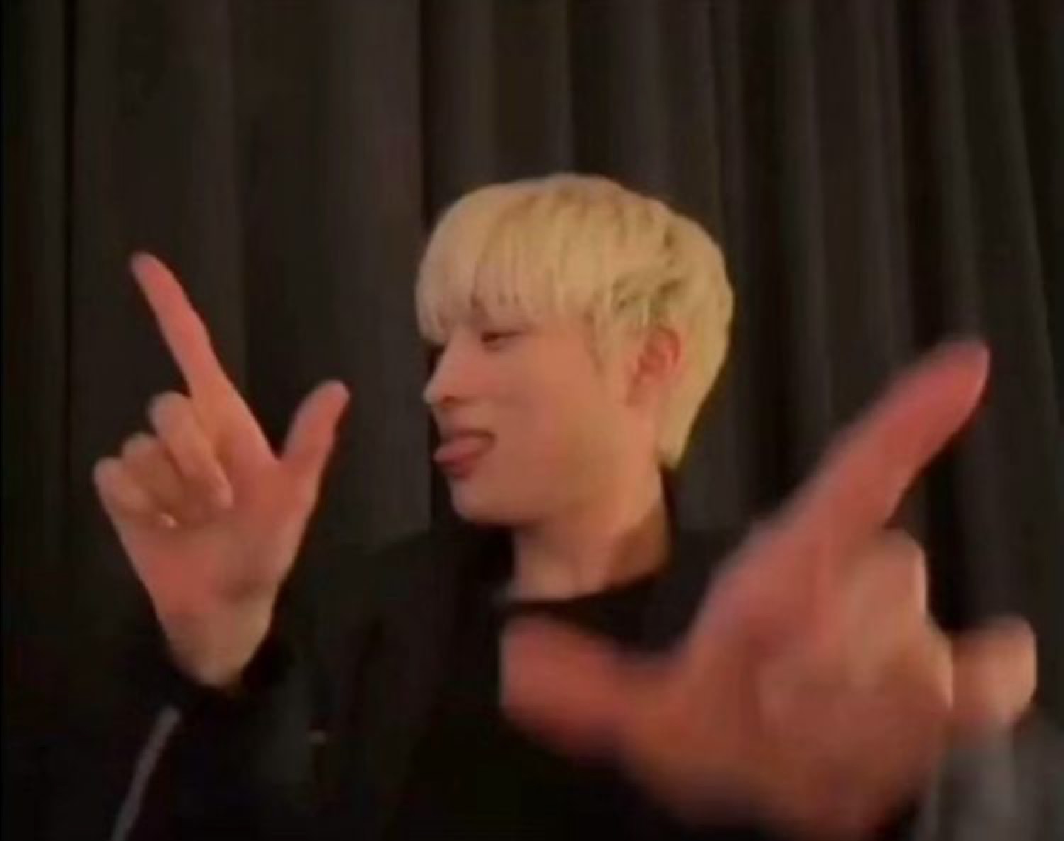 Blond man sticking his tongue out and pointing both fingers at the camera