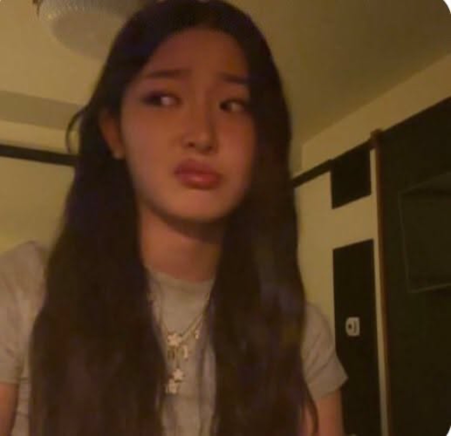 Girl in a dim room with a wobbly pout, right on the verge of tears