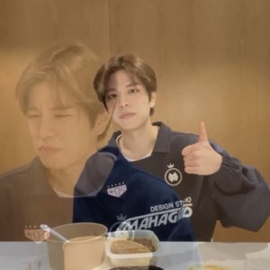 Guy in a navy jersey at a takeout table giving a flat, no-expression thumbs up