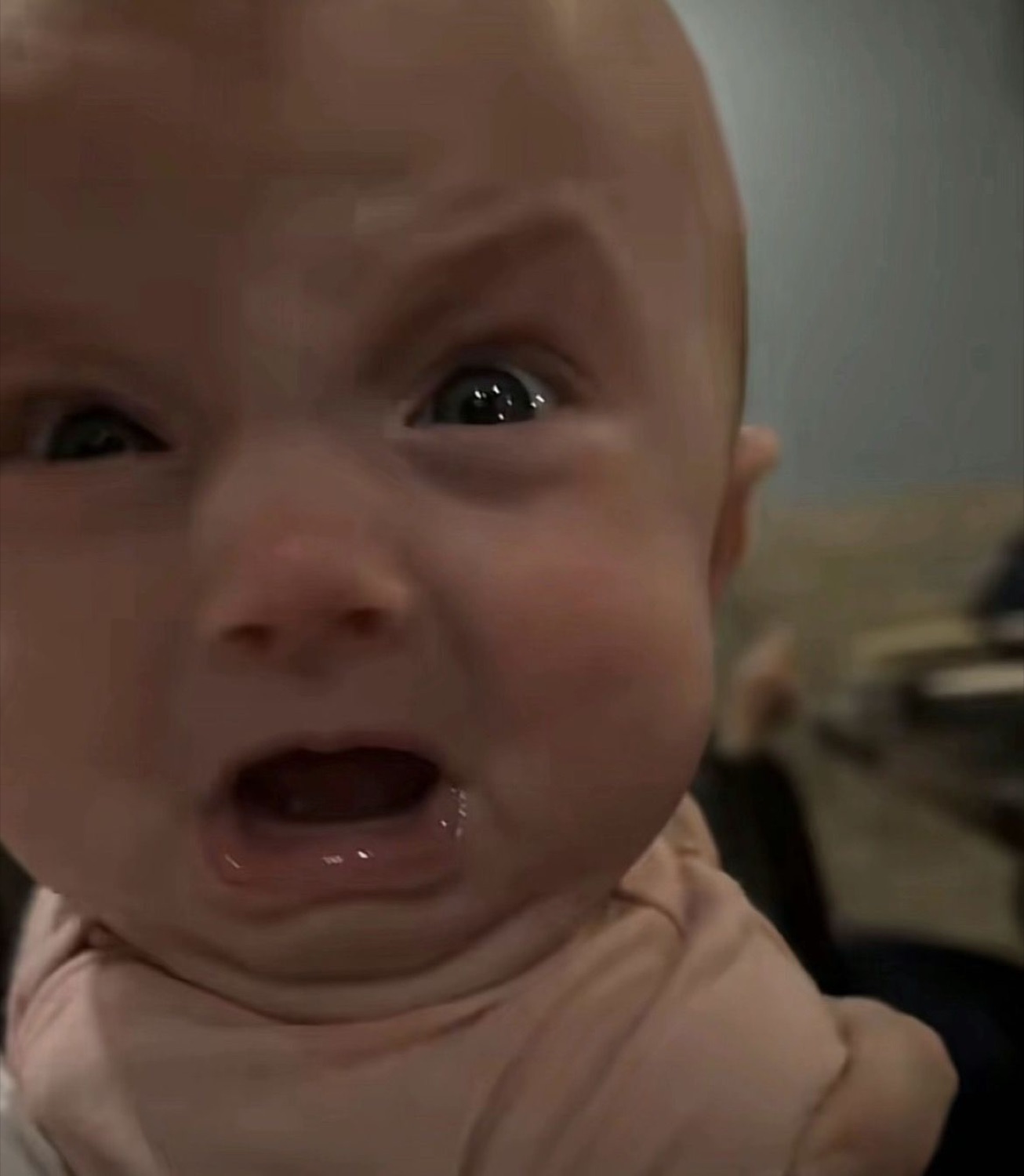 Close-up of a baby mid-cry with a terrified, teary face
