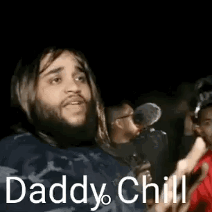 Bearded long-haired man waving his hand in a crowd, "Daddy chill"