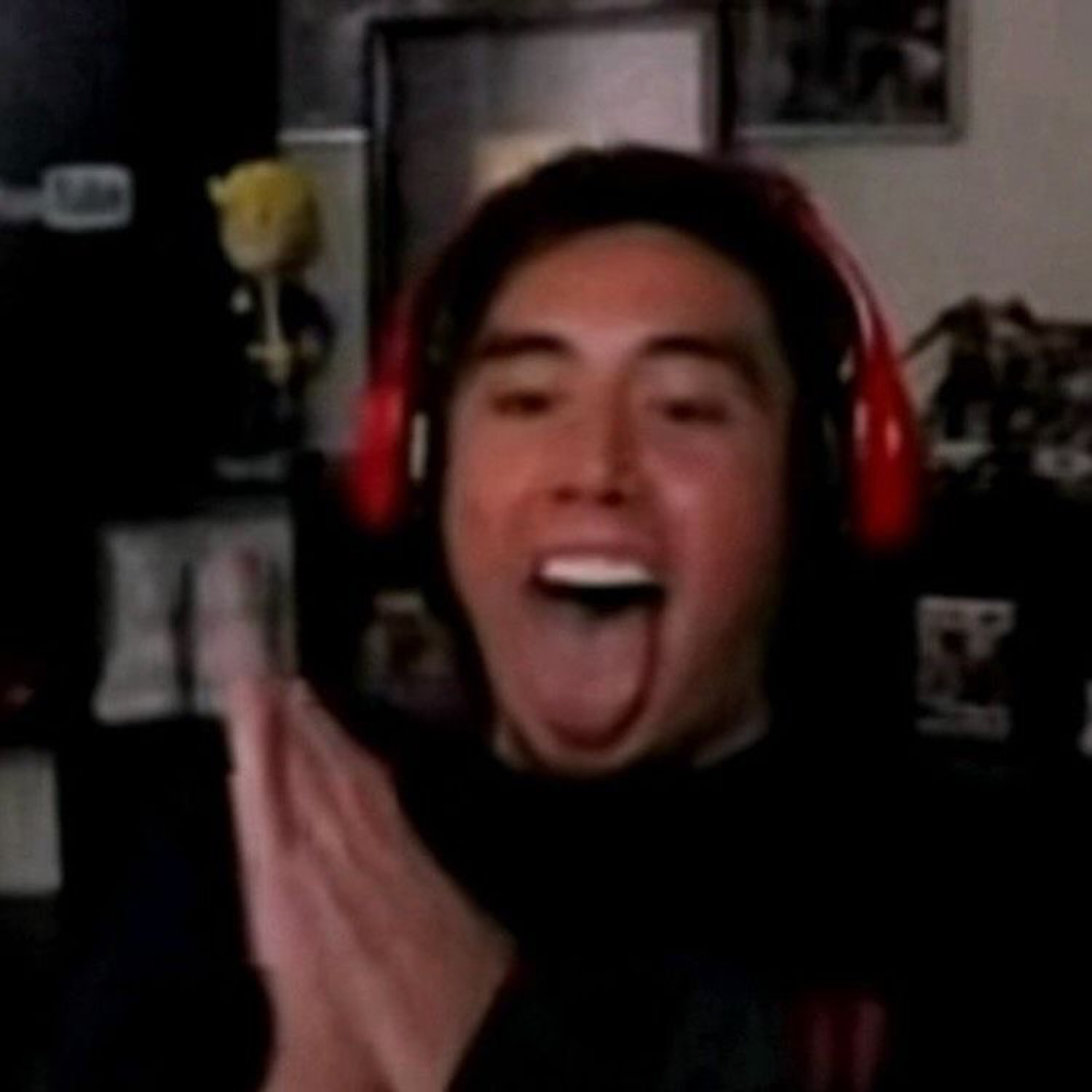 Guy in red gaming headphones laughing hysterically with hands raised