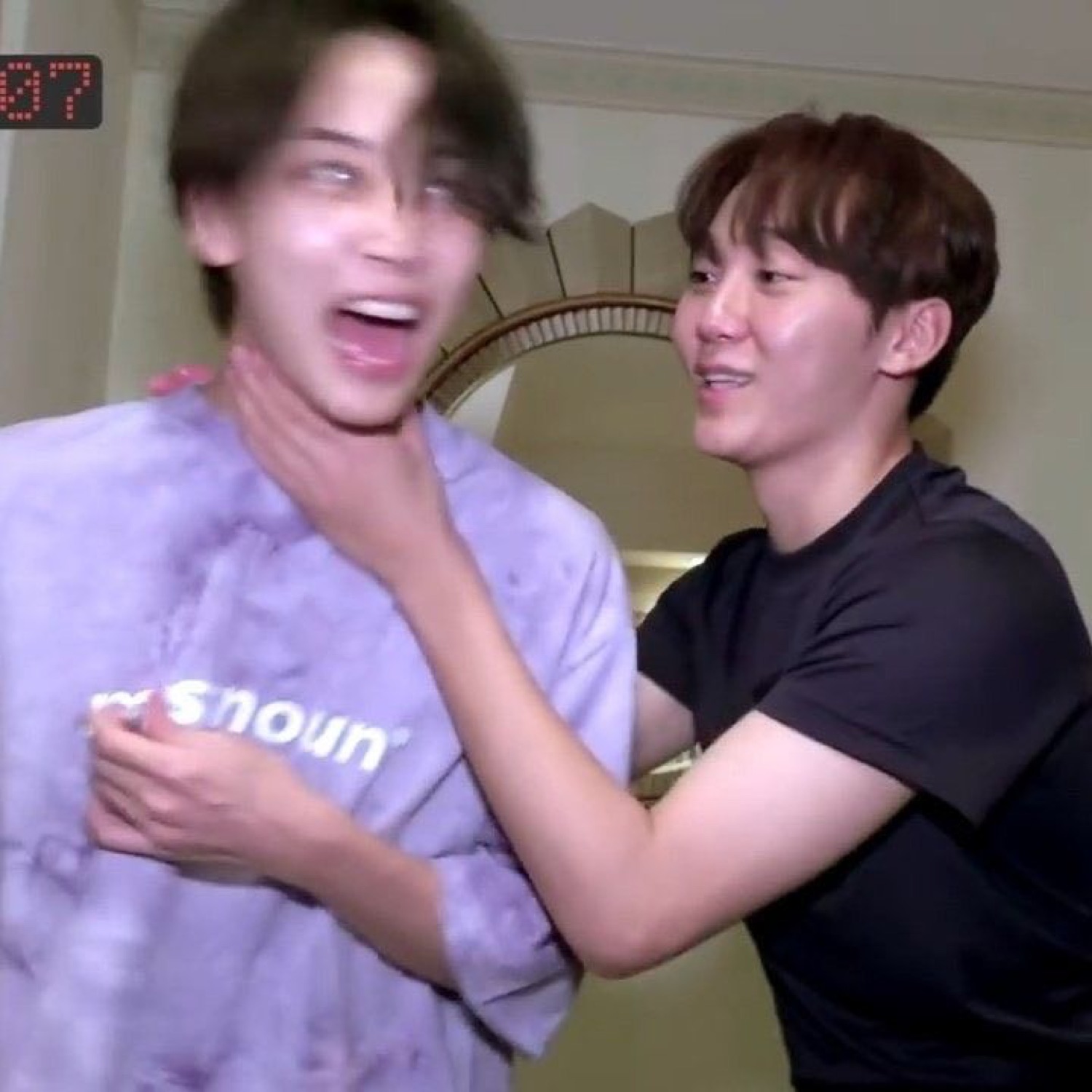 Two Korean guys cracking up — one completely losing it while the other grabs his neck