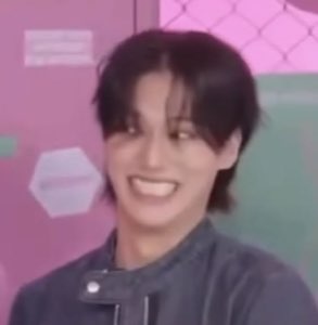 Young guy against a pink wall beaming with a huge toothy grin