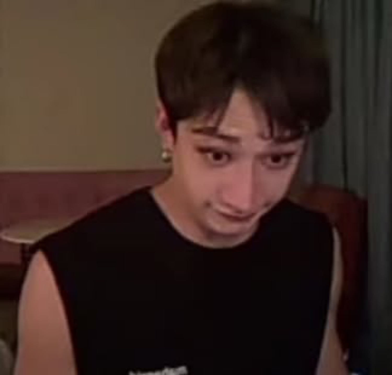 Young man in a black sleeveless shirt with teary eyes and a pained expression