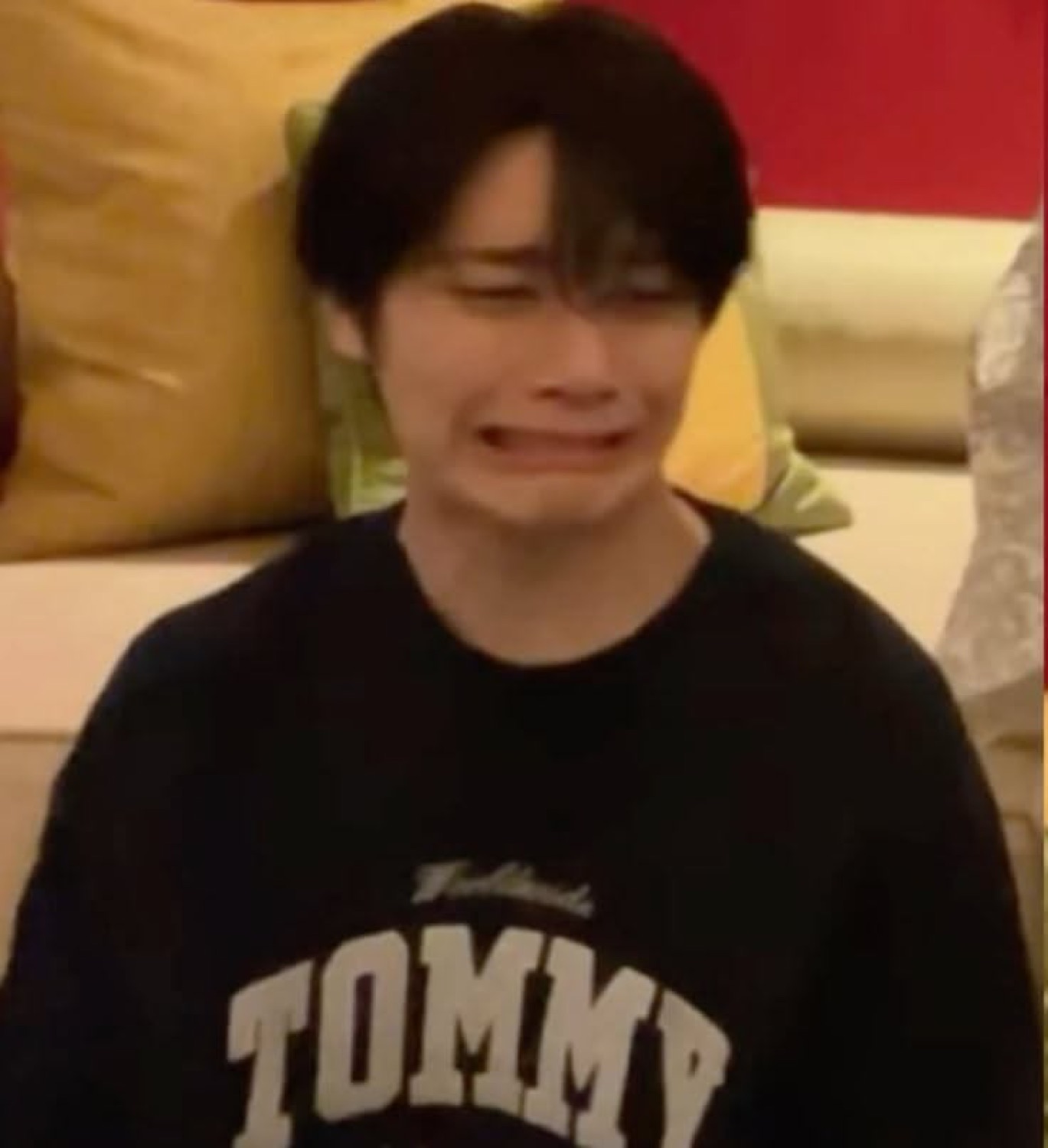 Guy in a Tommy sweatshirt with his face scrunched up, full-on ugly crying