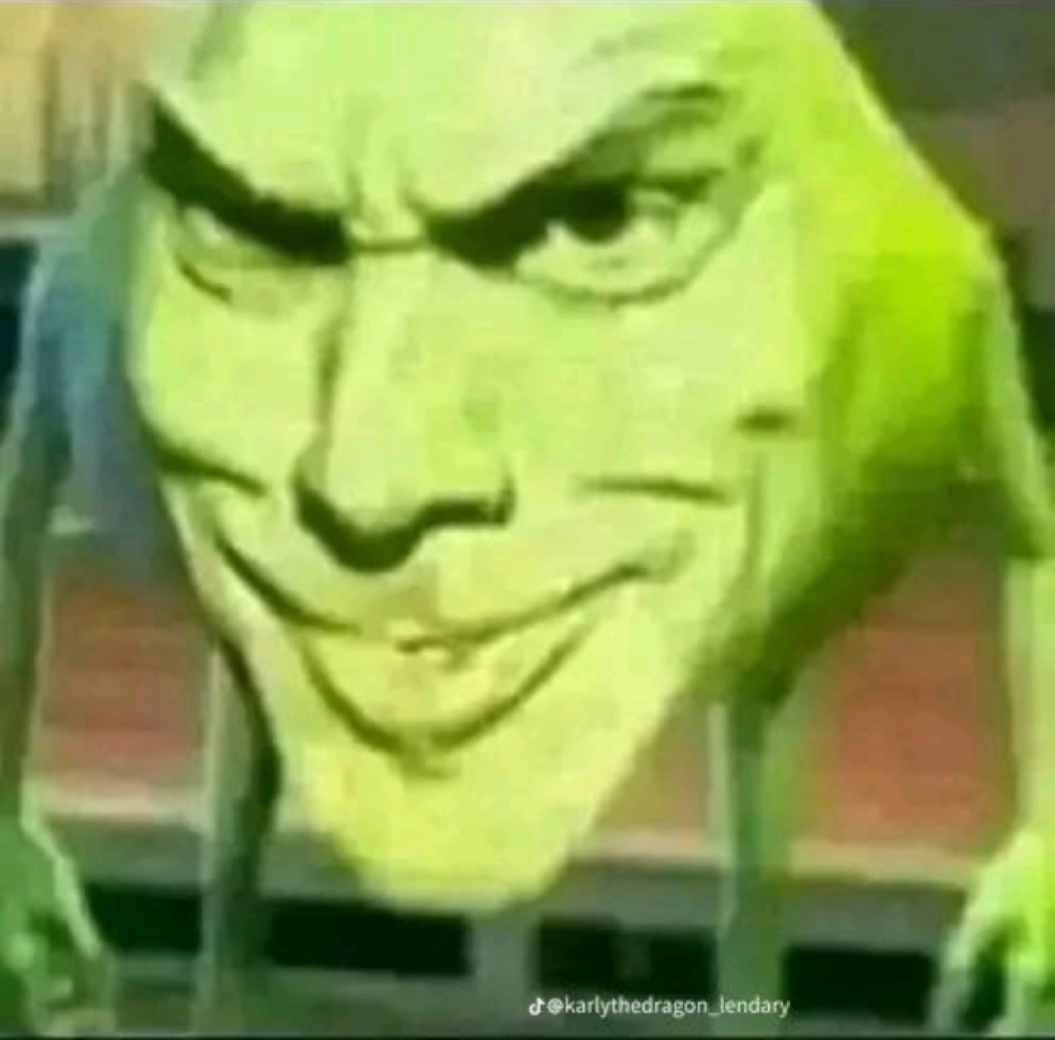 Green Mike Wazowski-like creature with an evil smug grin