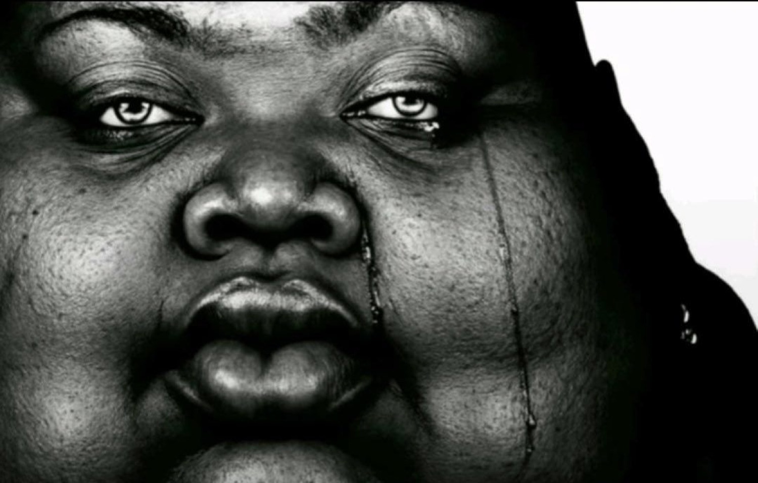 Black-and-white close-up of a woman with a tear running down
