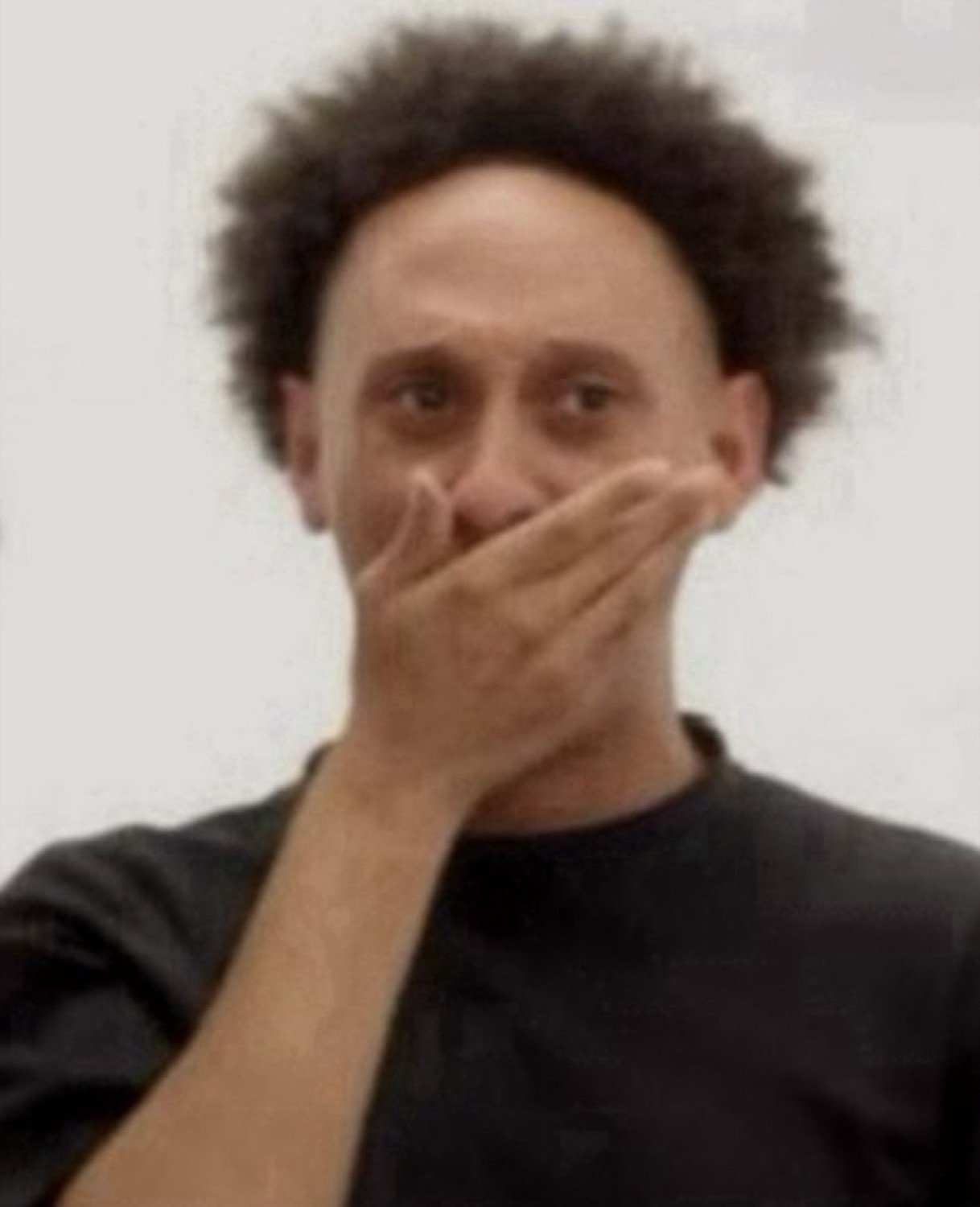 Man covering his mouth with his hand, eyes wide, clearly caught off guard