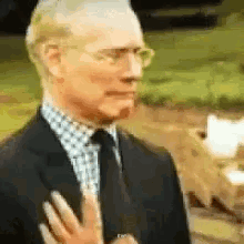 Older man in a suit grimacing and waving his hands no in disgust