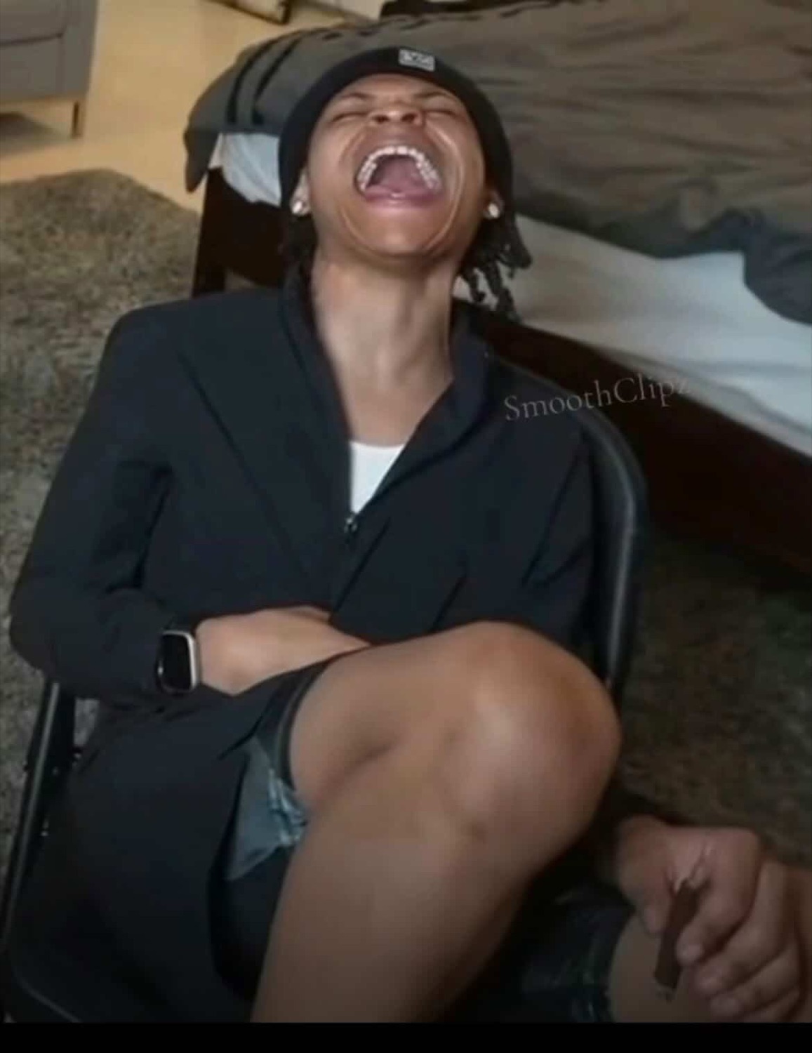 Young man leaning back in a chair, head tilted up, mouth wide open laughing hard