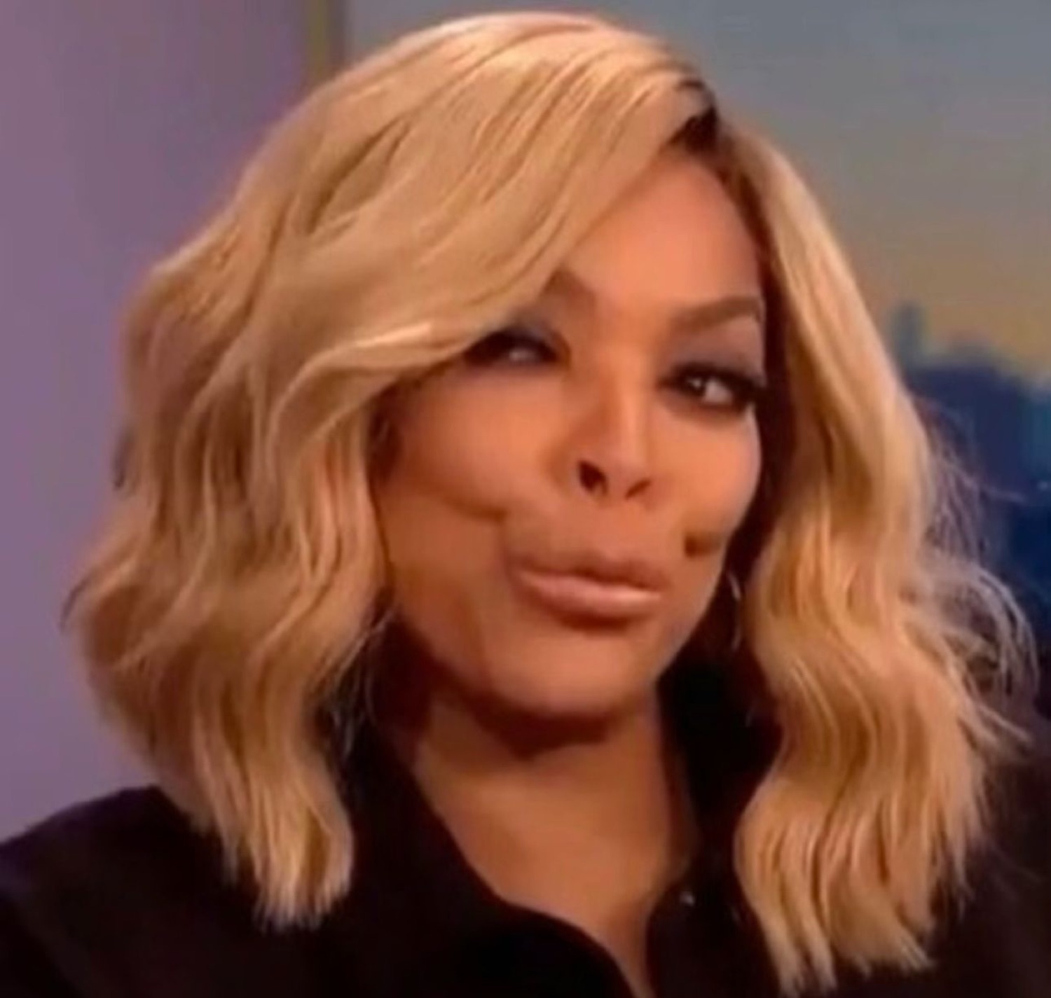 Blonde talk show host cutting a skeptical side-eye at something off camera