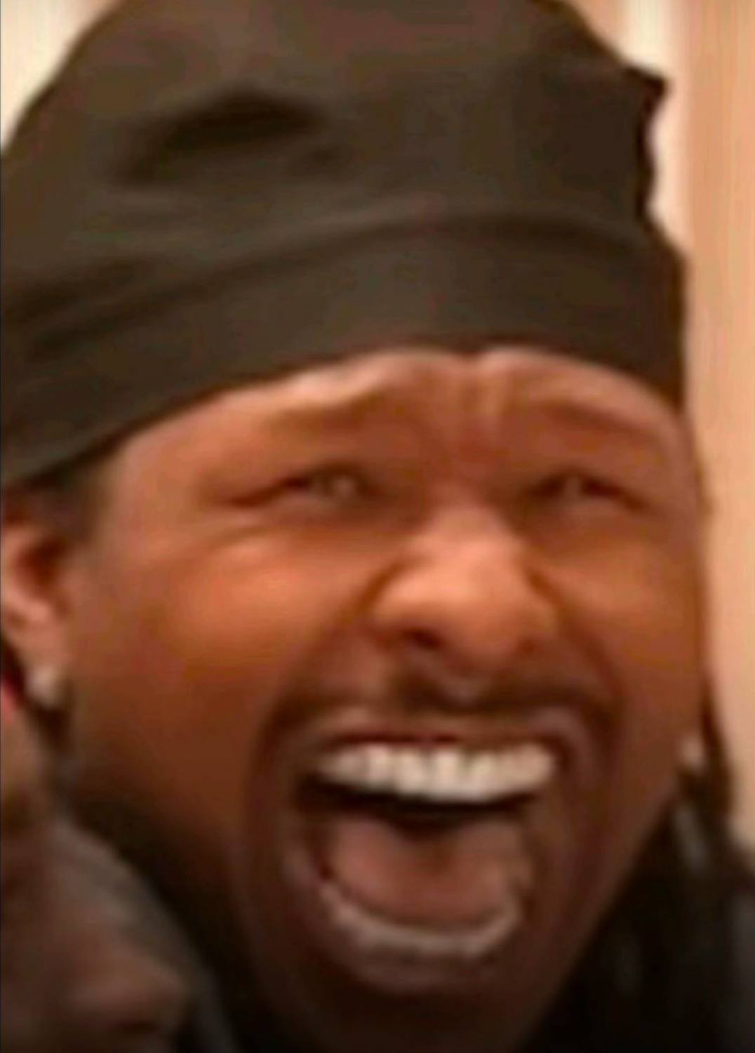 Man in a beanie cracking up with a wide open-mouthed laugh