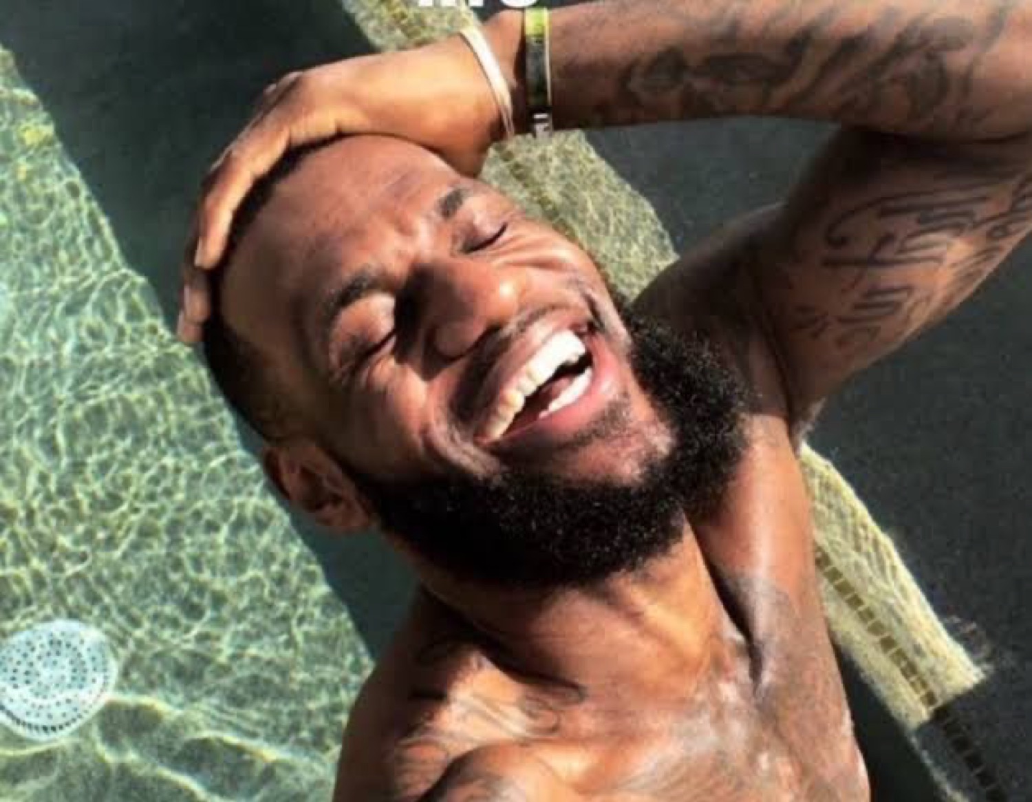 LeBron James shirtless by a pool throwing his head back laughing with pure joy