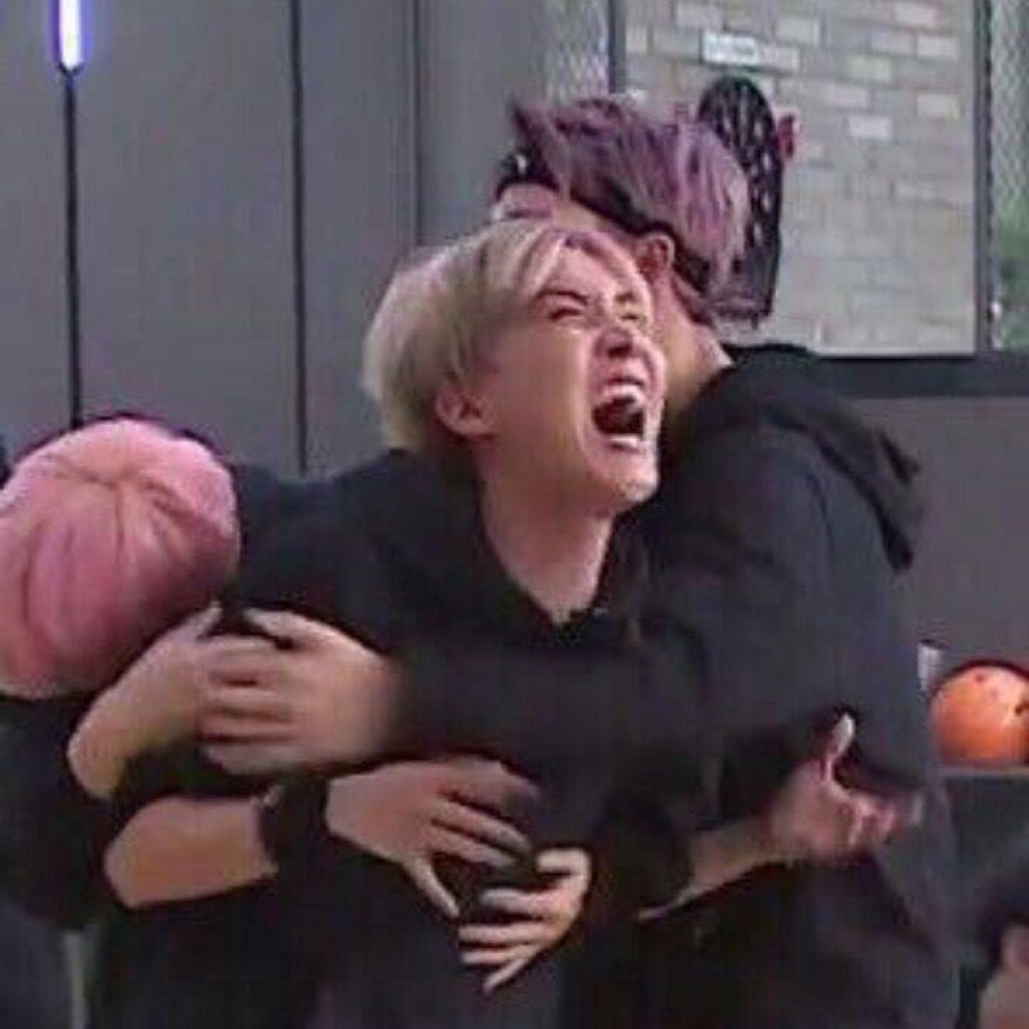 Blond person wailing while being hugged from behind, face scrunched in tears
