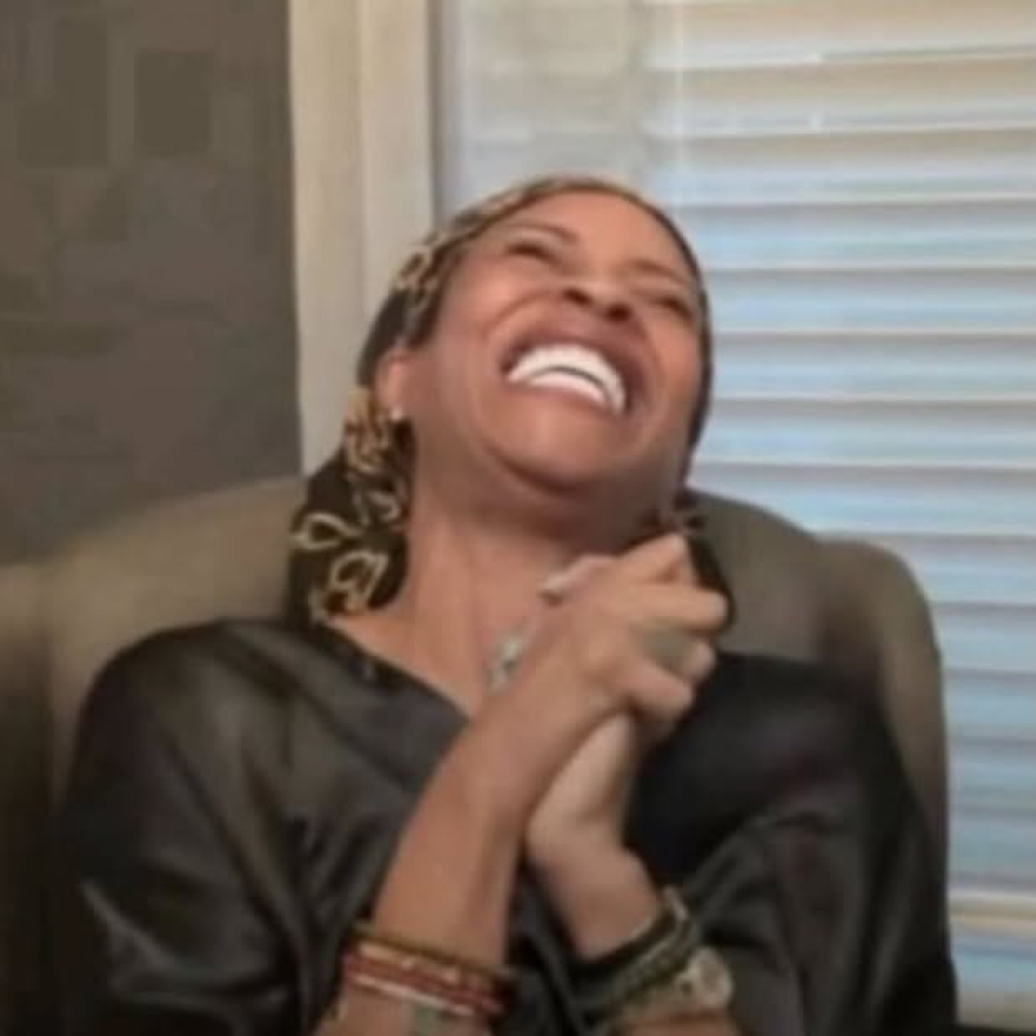 Woman laughing so hard she's leaning back with her hands clasped in pure delight
