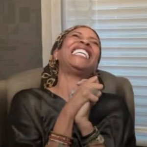 Woman laughing so hard she's leaning back with her hands clasped in pure delight
