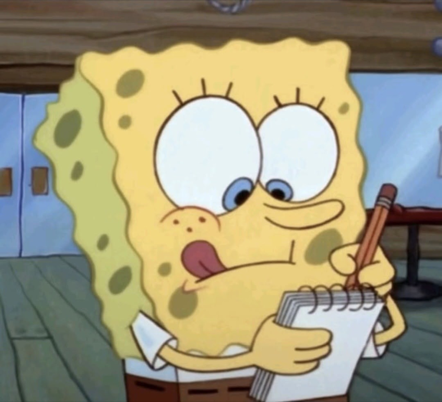 SpongeBob concentrating hard on a notepad, tongue out