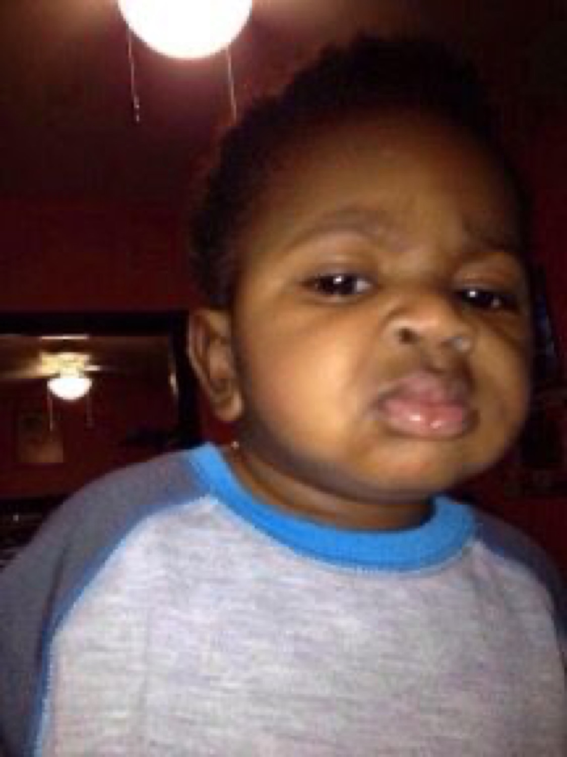 Toddler under a ceiling fan giving a deeply skeptical, unimpressed pout