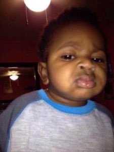 Toddler under a ceiling fan giving a deeply skeptical, unimpressed pout