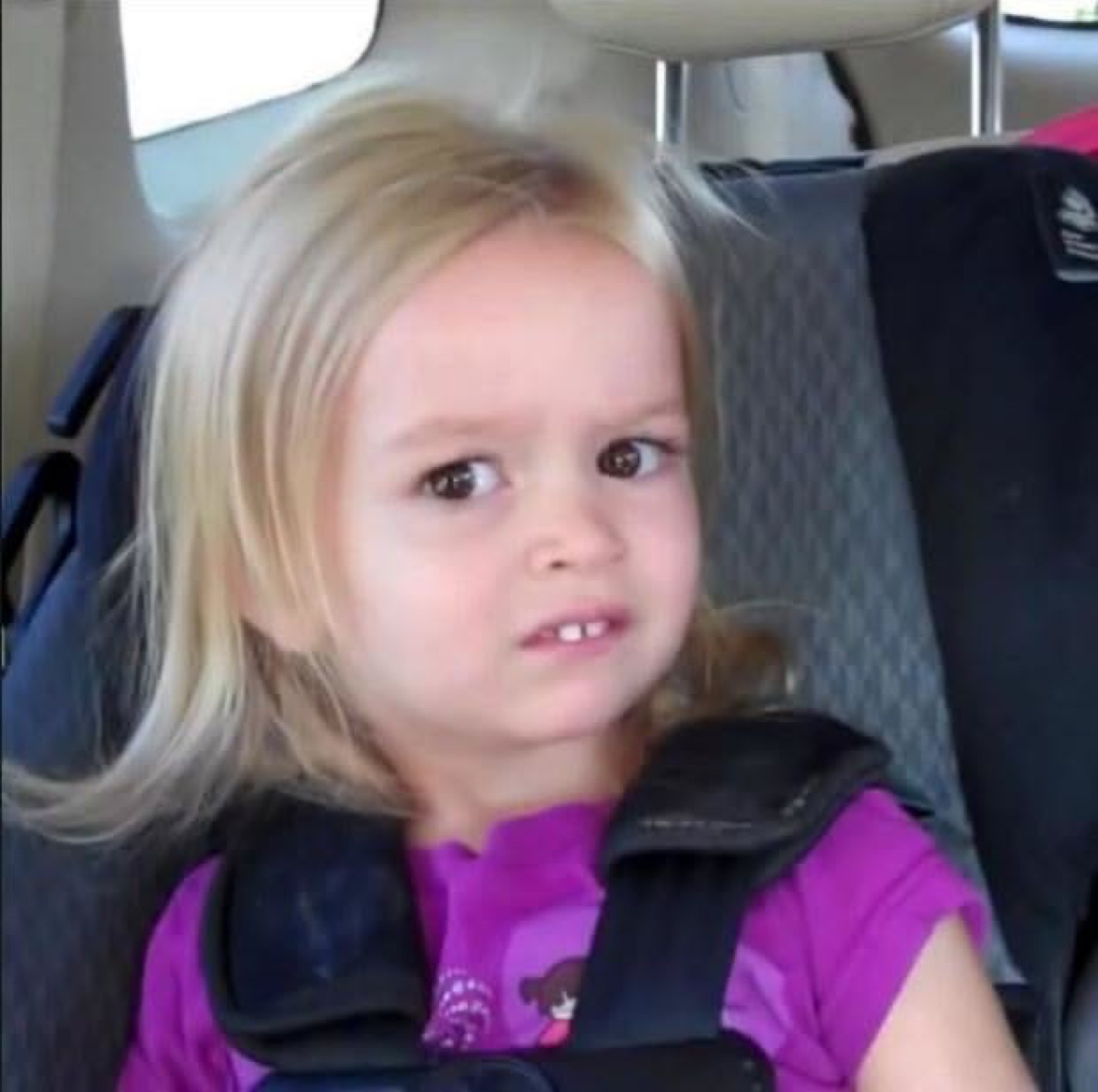 Little girl in a car seat side-eyeing with a deeply skeptical, let-down face