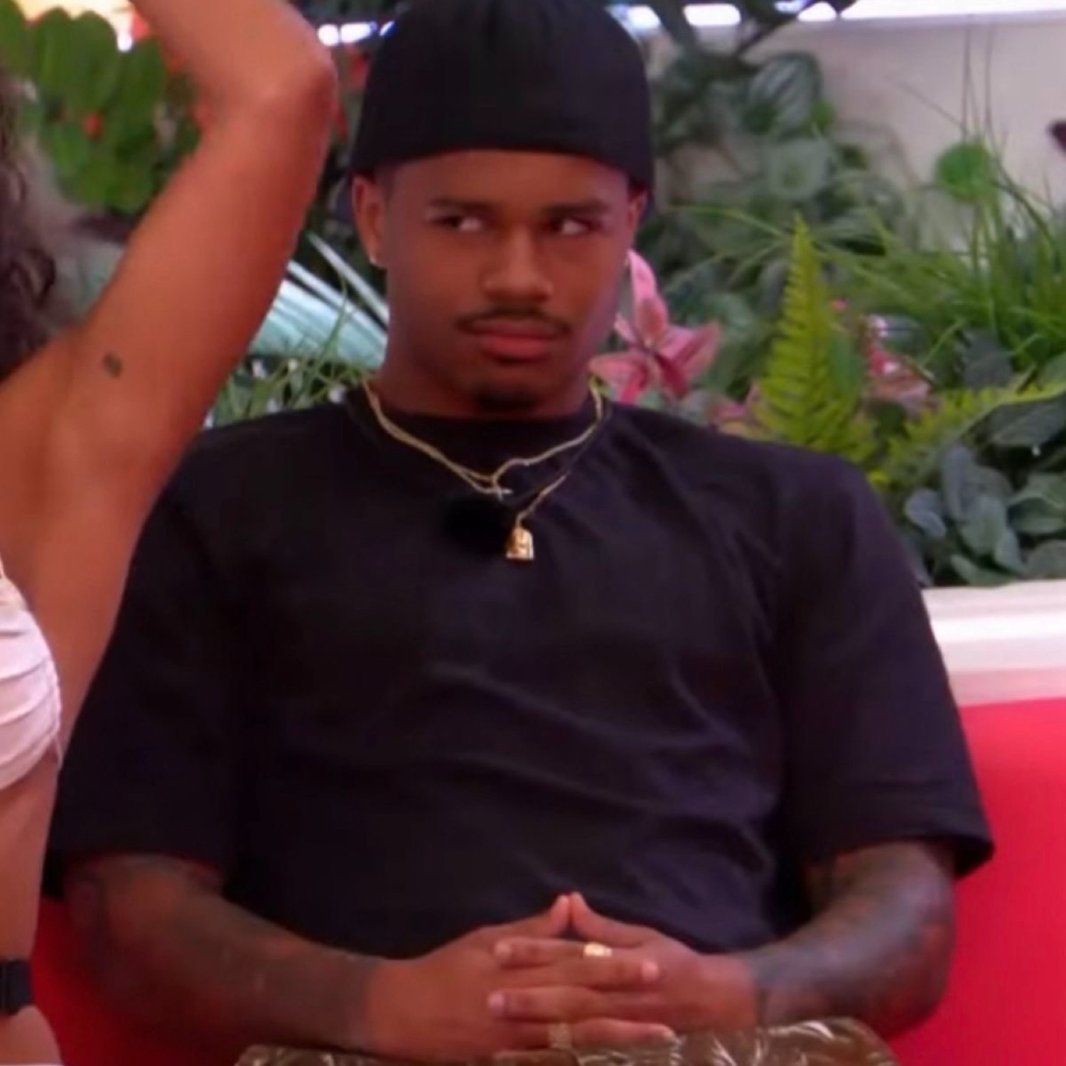 Guy on a reality show sitting arms folded, throwing a flat, unimpressed side-eye