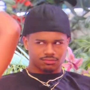 A young man in a durag cutting a suspicious, judgmental side-eye off camera