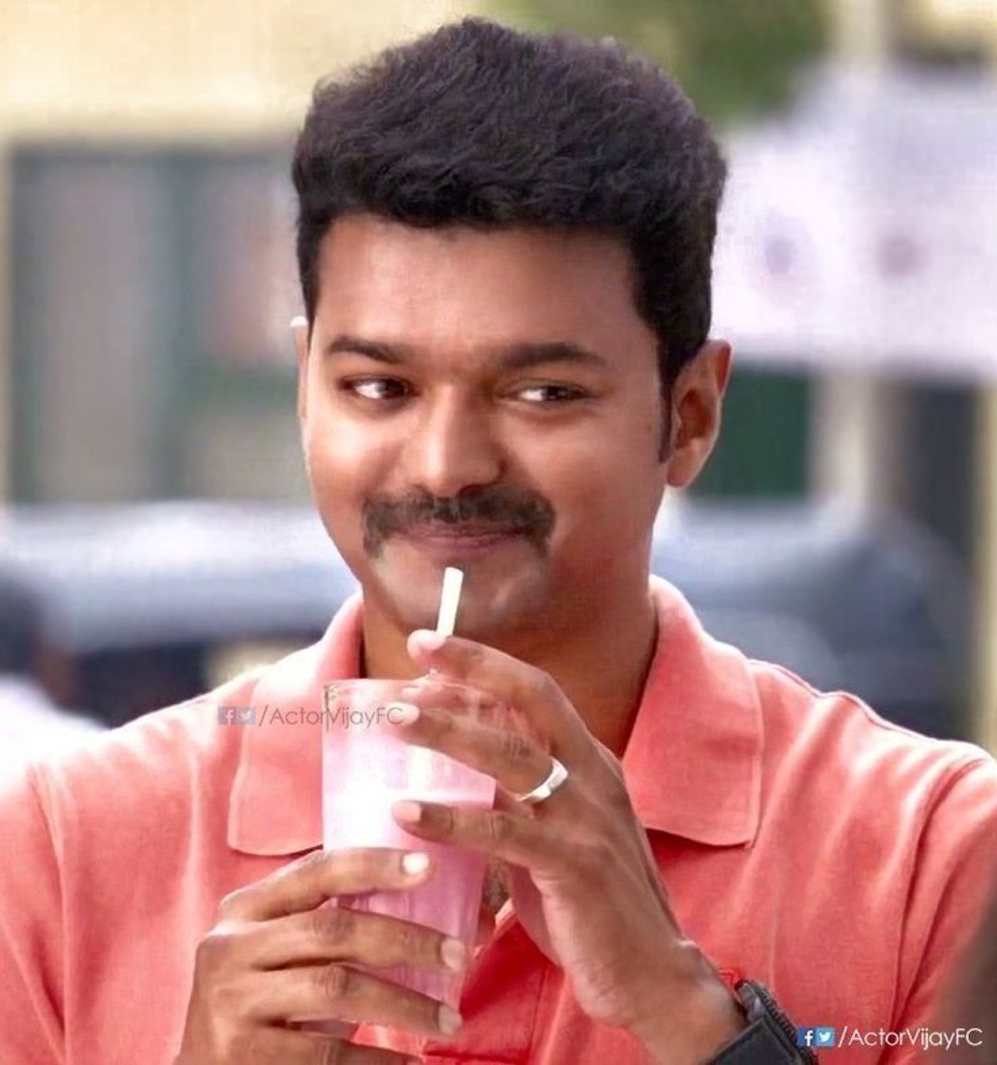 Vijay sipping a pink milkshake through a straw with a smirk