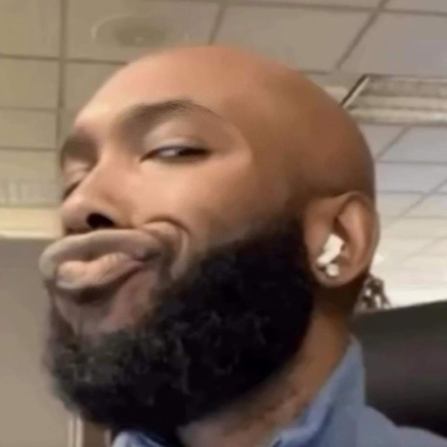 Bald bearded guy in an office pursing his lips and cutting a knowing side-eye