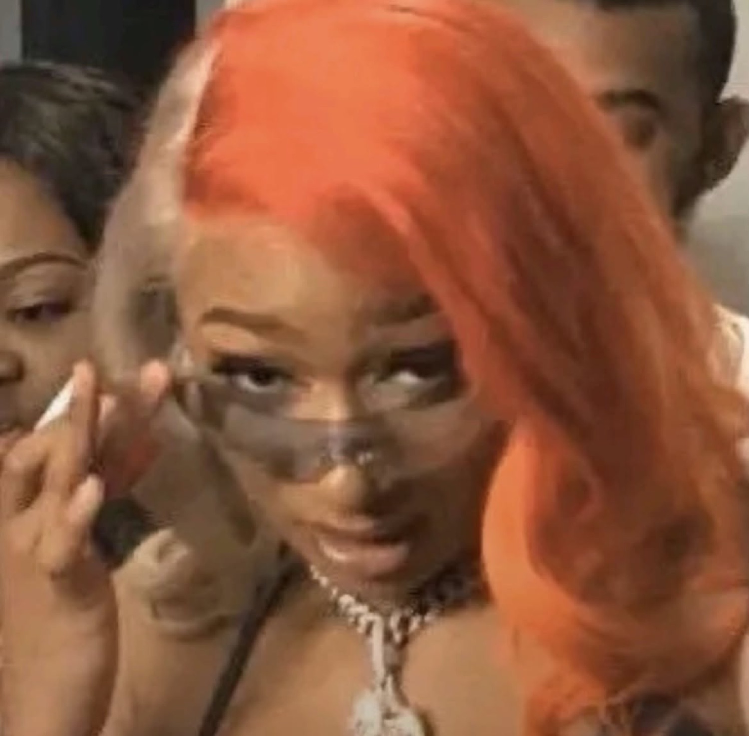 Woman in a bright orange wig and tiny sunglasses throwing a slow, judgmental side-eye