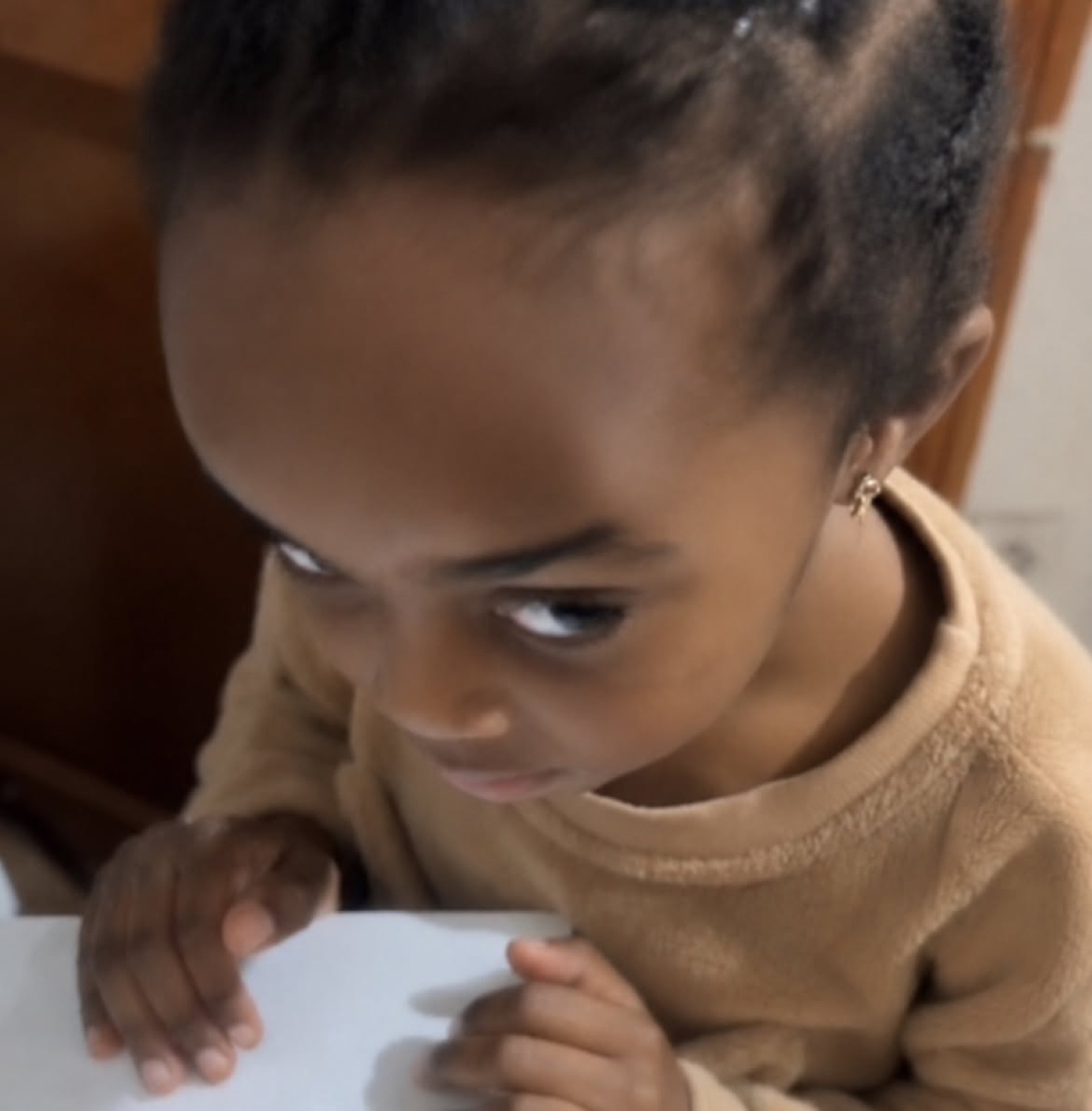Toddler leaning on a table giving an intense side-eye with a scheming look
