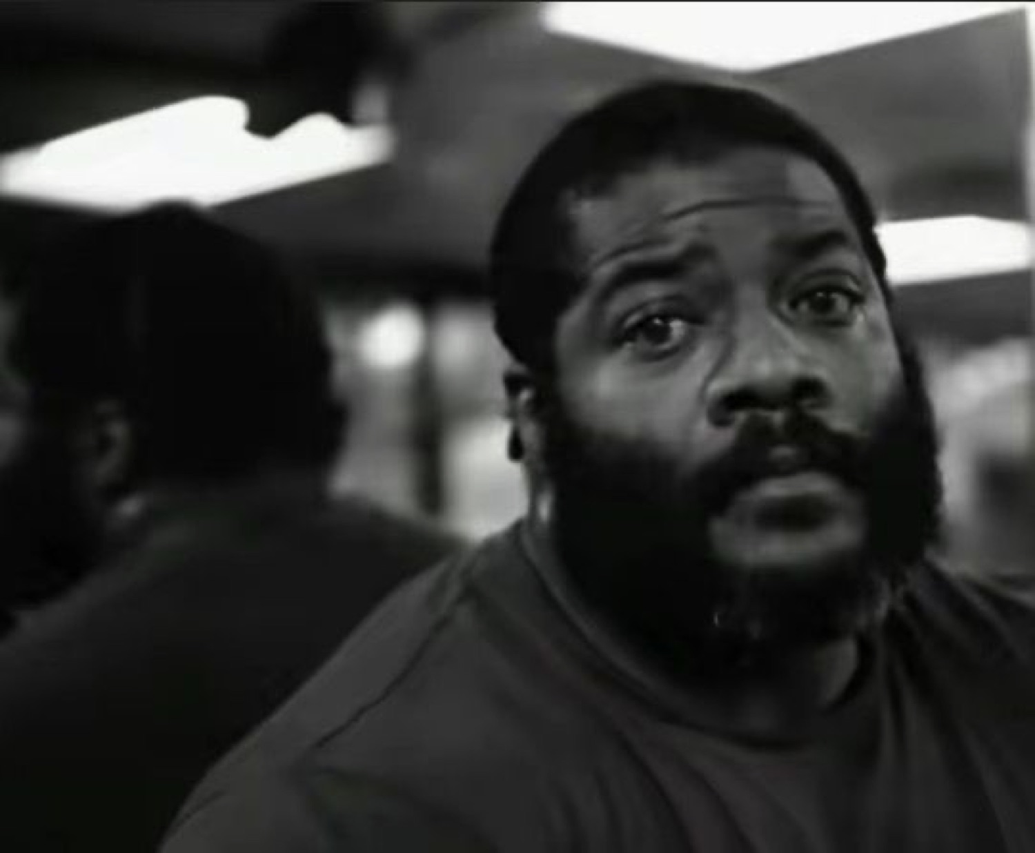 Black-and-white shot of a bearded man staring blankly ahead, dead inside