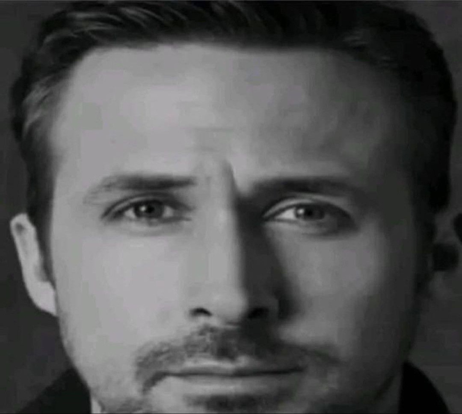 Ryan Gosling in black and white, staring you down with quiet intensity