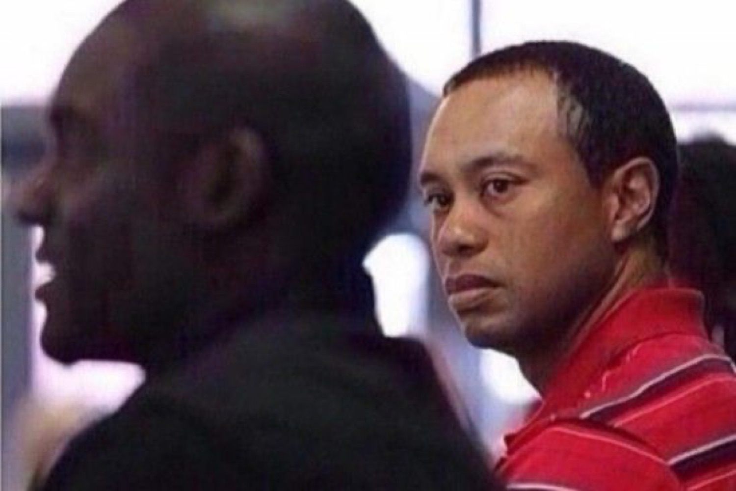 Tiger Woods cutting a sharp side-eye glance in a red polo shirt