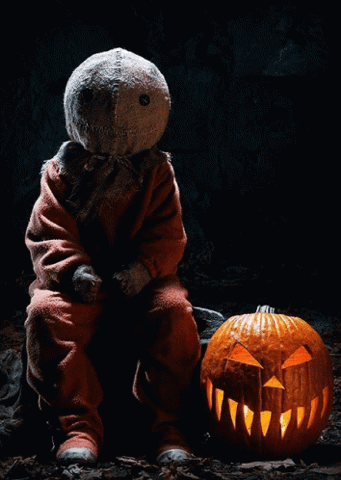 Sam from Trick 'r Treat sitting beside a glowing jack-o-lantern